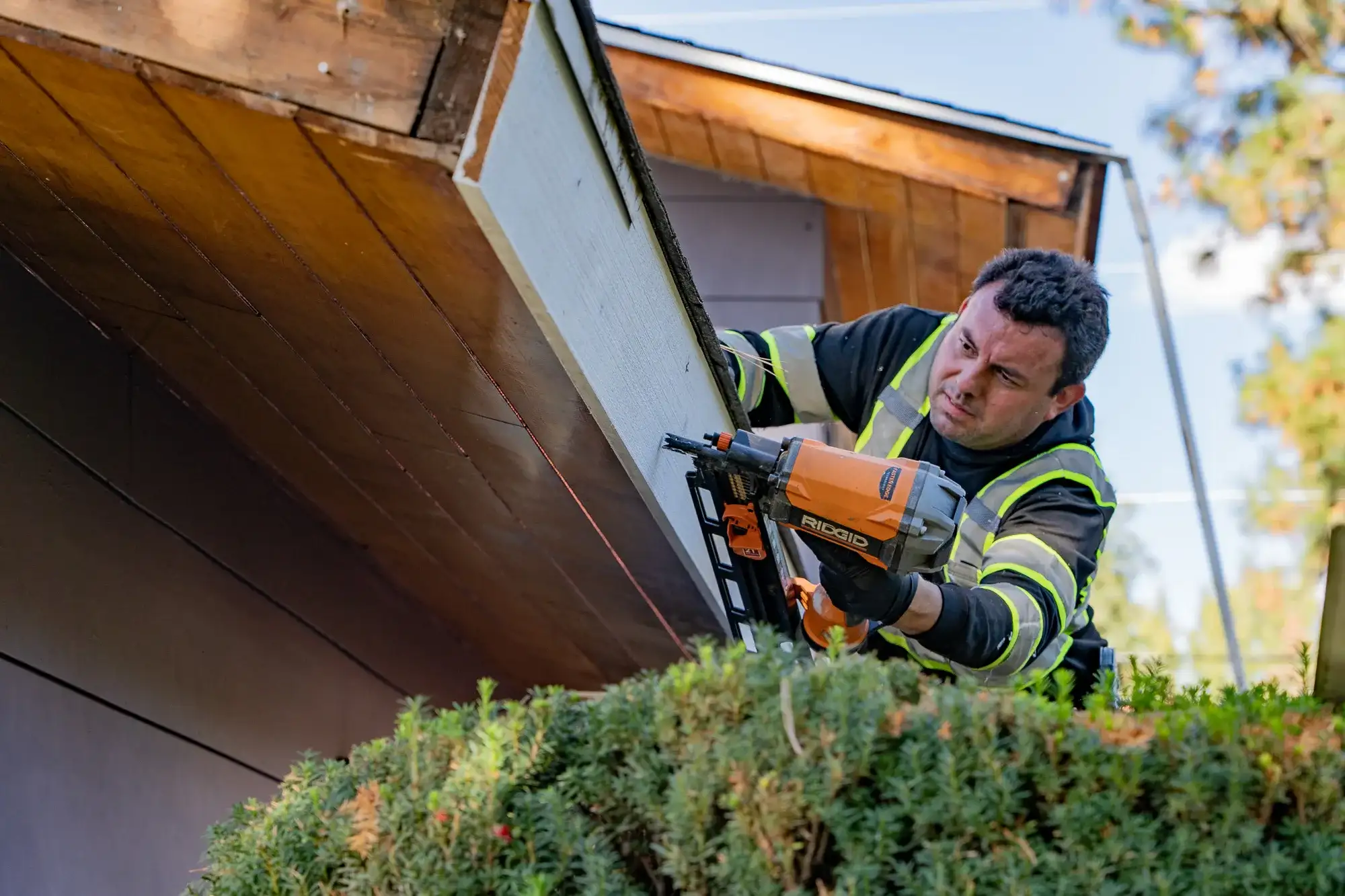 Casa Vida crew member nailing a new fascia board in place with a nail gun