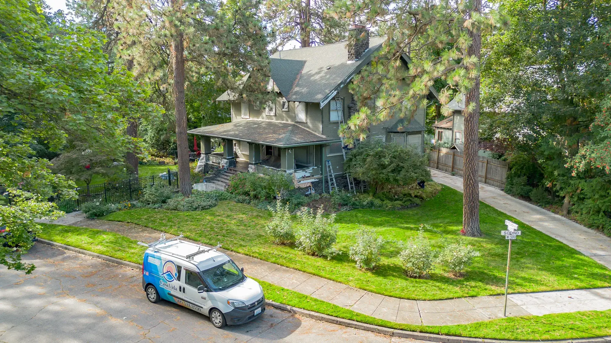 Drone view of the Casa Vida van parked at the curb in front of a green Craftsman home in Spokane