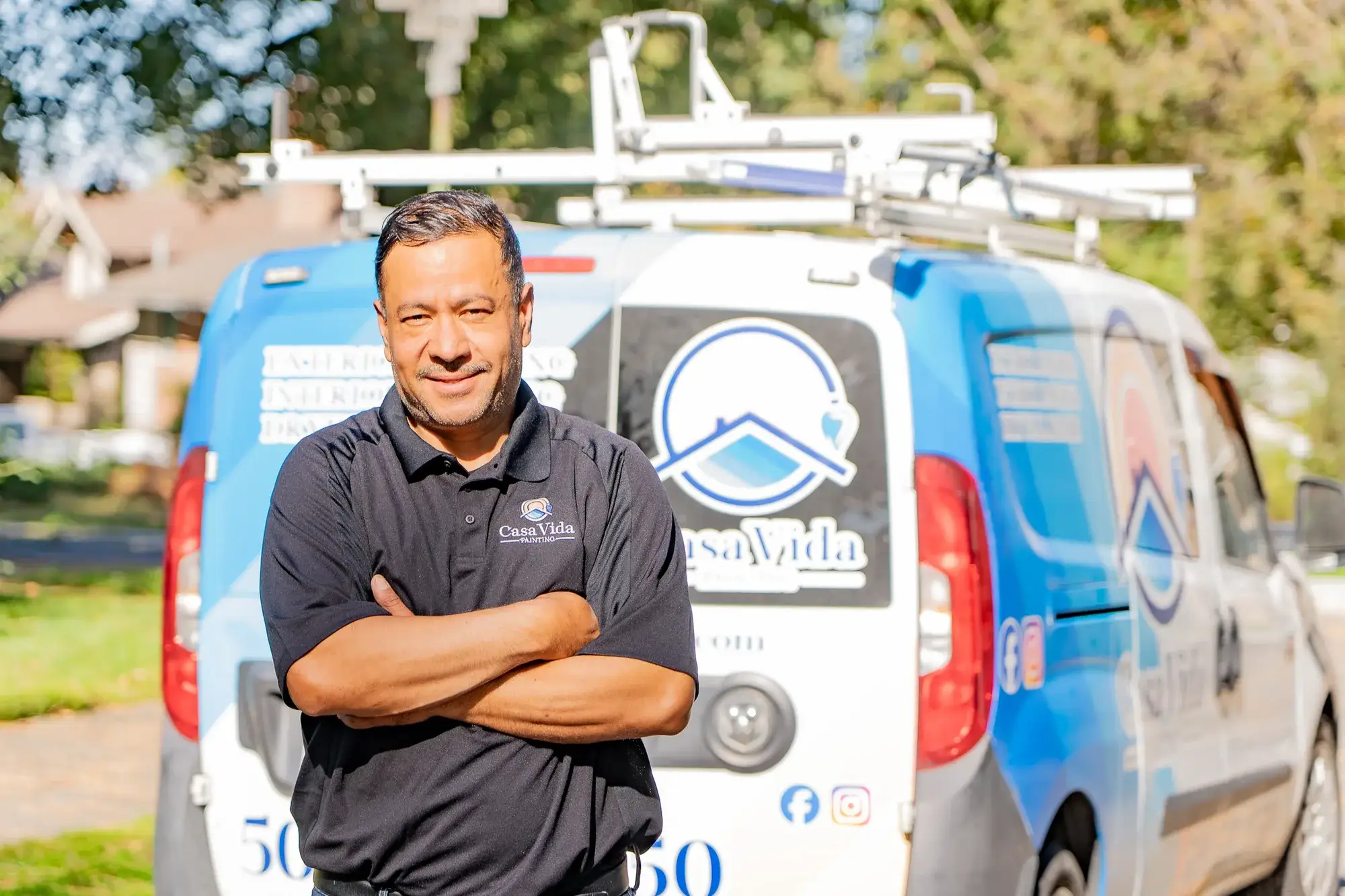 Victor, owner of Casa Vida, standing with his arms crossed in front of the company van