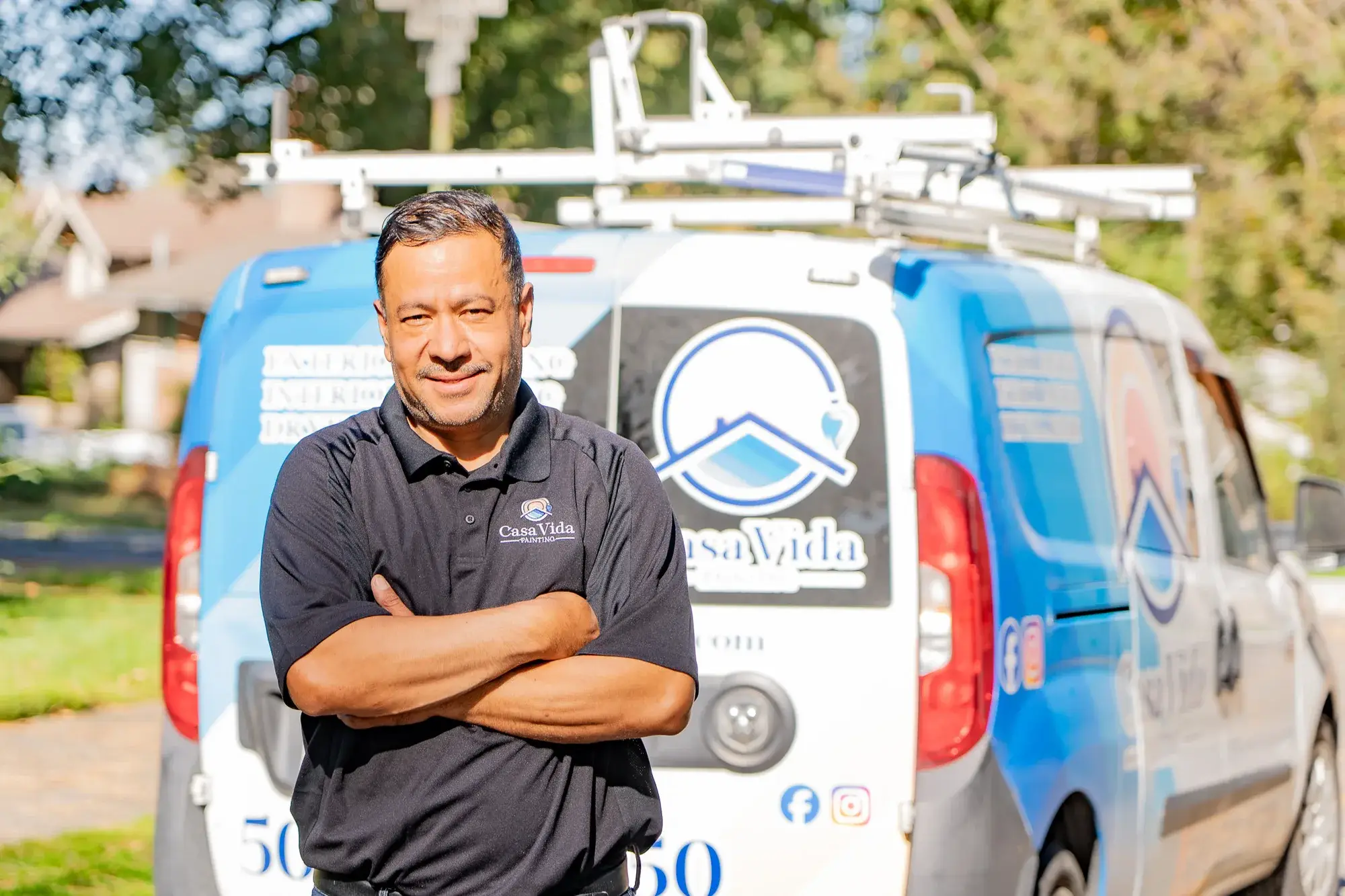 Victor, owner of Casa Vida, standing with his arms crossed in front of the company van