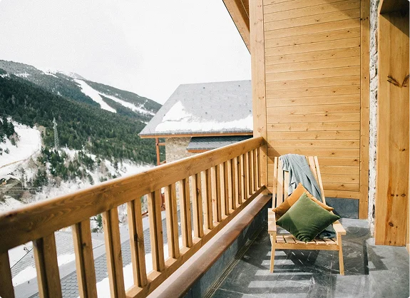 Wooden balcony with chair overlooking snowy mountain landscape