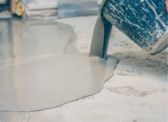 Liquid self-leveling floor compound being poured onto a surface from a container